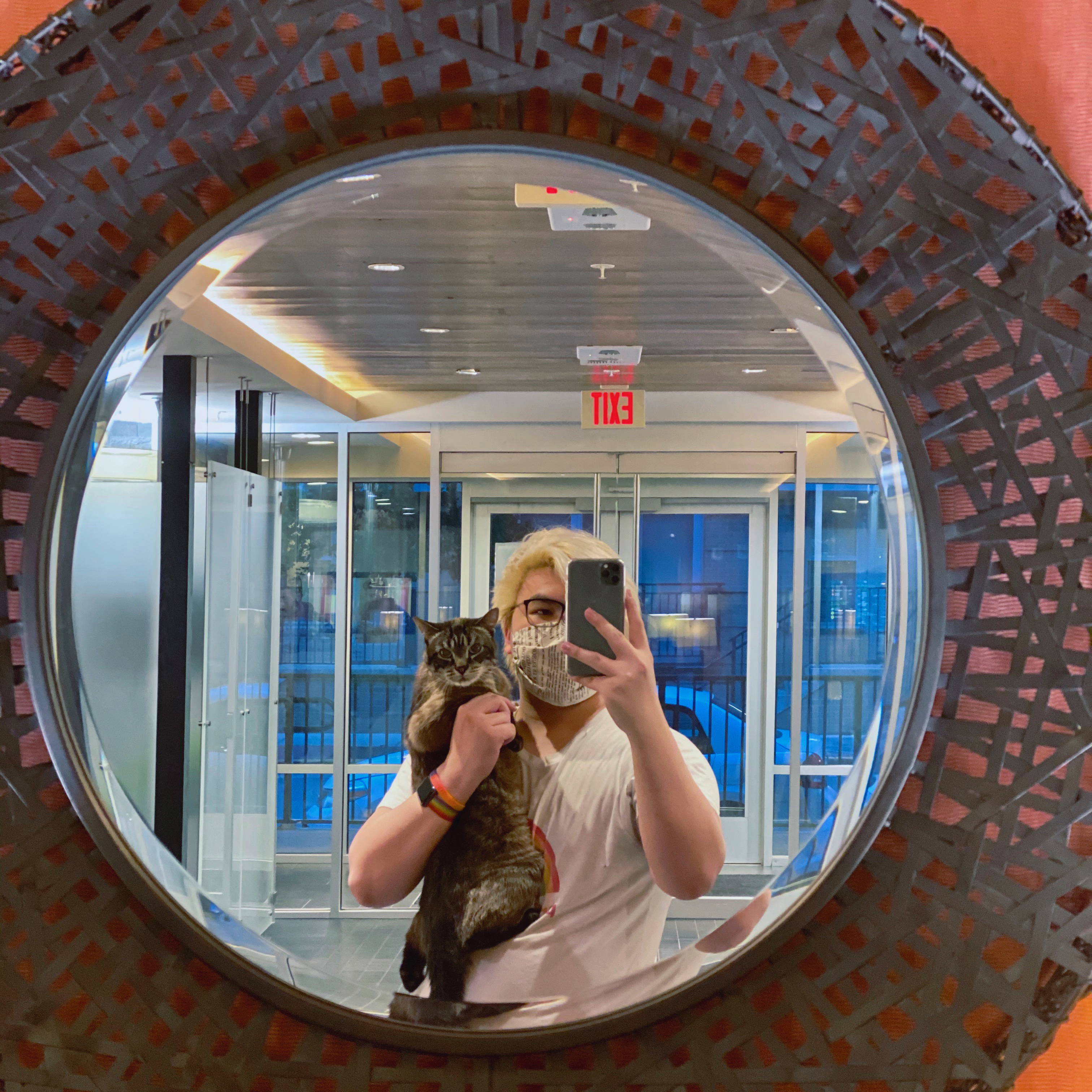 Max Gross and his cat, Troy, in a rounded mirror.